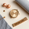 Rose gold stainless steel band watch resting on a light neutral background with soft reflections