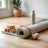 Eco-friendly yoga essentials including a rolled mat, cork blocks, and a strap with a water bottle nearby