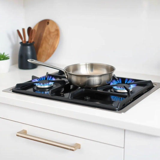 Blue flames on a modern gas cooktop with a stainless pan, showing efficient burner performance