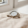 Bracelet-style wristwatch with metal links and clean dial on a neutral fabric background