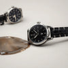 Men’s wristwatch with water droplets beading on the case and crystal on a neutral surface