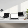 Three modern laptops on a minimalist desk with open screens under soft natural light
