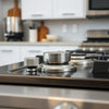 Metal gas stove control knobs on a stainless cooktop with a clean, minimal kitchen background