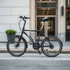 26-inch wheel folding bike parked upright on an urban sidewalk with a compact folded frame