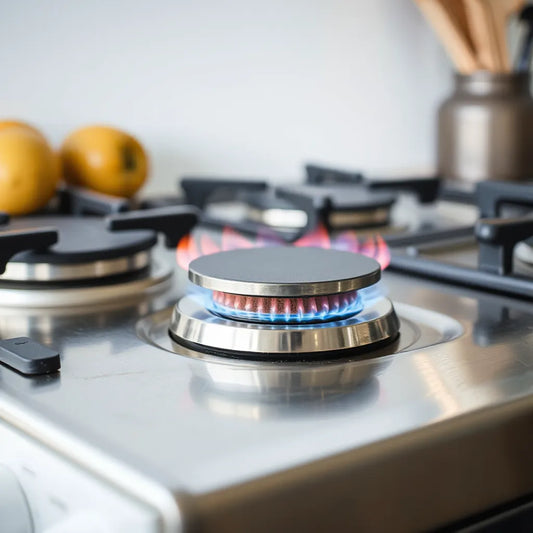 Modern gas cooktop with auto ignition knob and a small steady flame on a clean stainless surface