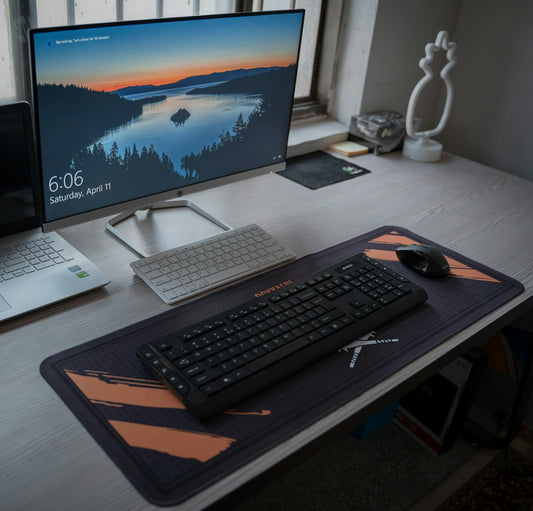 A computer monitor and keyboard on a desk with a large mouse pad
