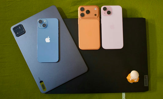 Three iphones and a tablet on a green surface