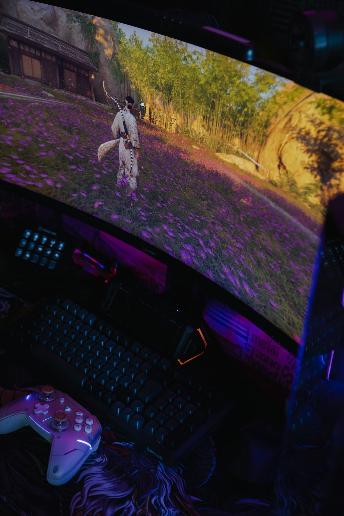 Gaming setup with a curved monitor, keyboard, and controller.